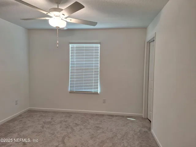 an empty room with a window and a fan