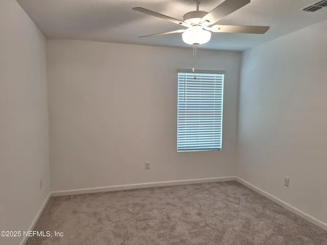 an empty room with a window and a fan