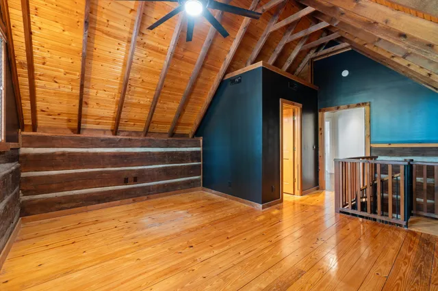 a view of an empty room with wooden floor fireplace and a window