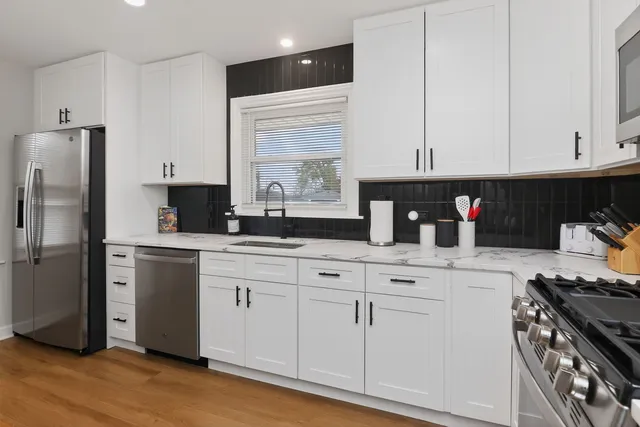 a kitchen with stainless steel appliances granite countertop a refrigerator sink and white cabinets