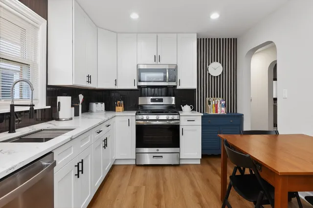 a kitchen with stainless steel appliances a stove a sink cabinets and a refrigerator