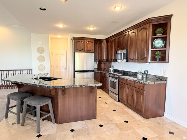 1562 Fairway Ridge Road Draper, UT 84020 - Photo 17 of 60 Kitchen featuring a central island with an integrated sink, granite countertops, and rich wood-finish cabinetry