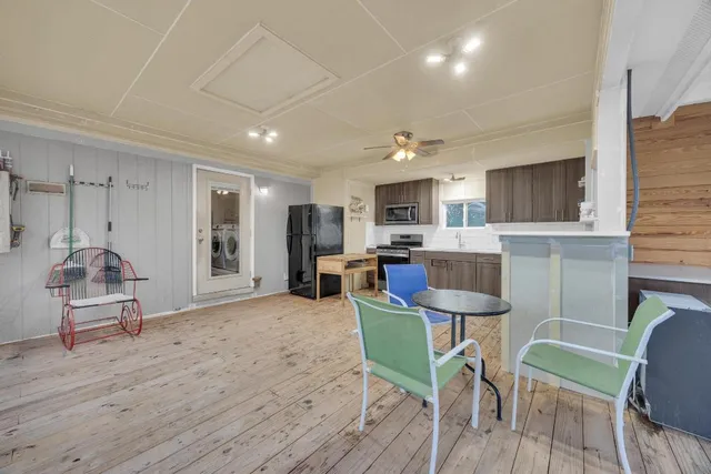 a living room with furniture a dining table wooden floor and kitchen view