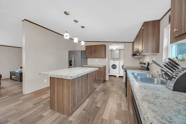 a kitchen with stainless steel appliances granite countertop wooden cabinets a sink dishwasher a stove and a refrigerator