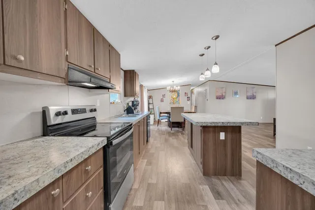 a kitchen with granite countertop a sink a counter top space stainless steel appliances and cabinets