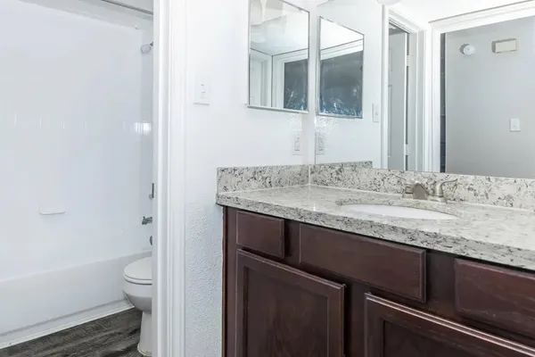 a bathroom with a granite countertop sink a toilet and shower
