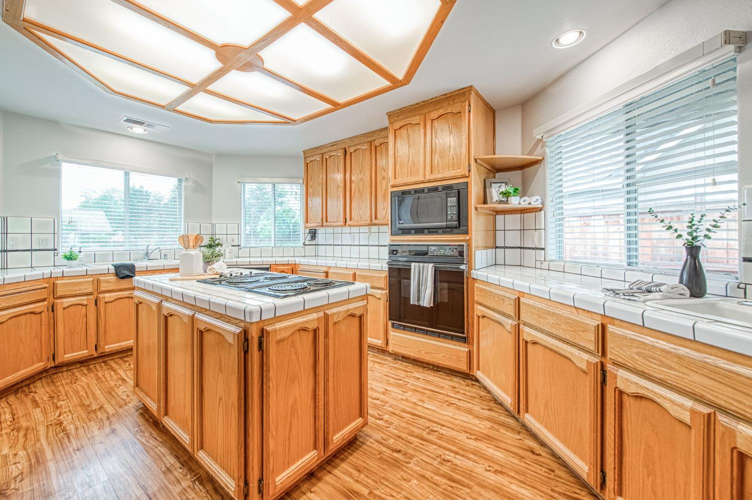 3225 Filbert Avenue Clovis, CA 93611 - Photo 14 of 36 a kitchen with granite countertop a stove top oven a sink dishwasher and wooden cabinets with wooden floor