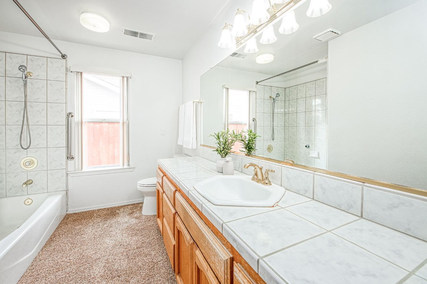 3225 Filbert Avenue Clovis, CA 93611 - Photo 22 of 36 a spacious bathroom with a granite countertop sink a large mirror and a bathtub with shower