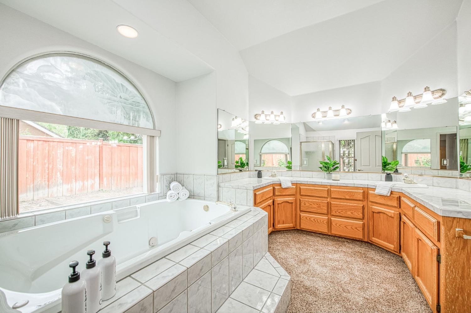 3225 Filbert Avenue Clovis, CA 93611 - Photo 30 of 36 a large bathroom with a granite countertop tub a double vanity sink a window and a mirror