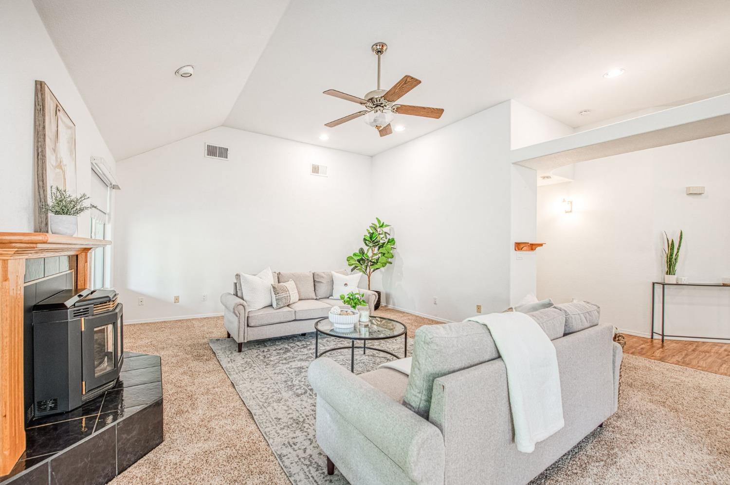 3225 Filbert Avenue Clovis, CA 93611 - Photo 8 of 36 a living room with furniture a fireplace and a chandelier