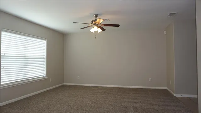 an empty room with windows and fan