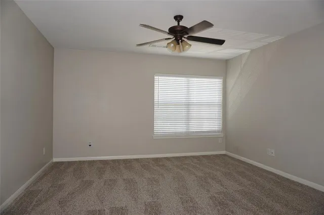 a view of a room with a ceiling fan and windows