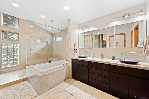 a en suite bathroom with a tub double sink window and mirror