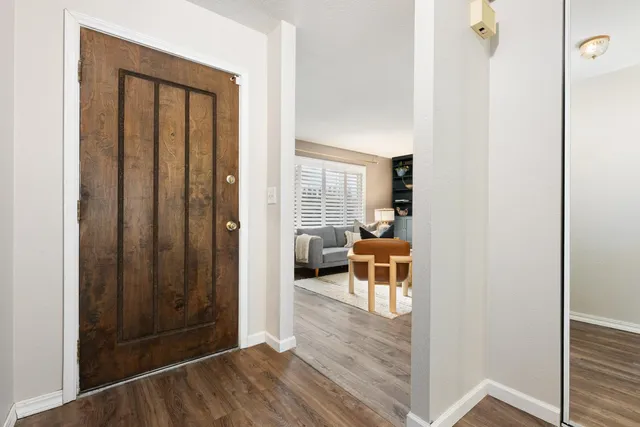 a view of a hallway with wooden floor and a living room
