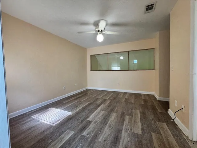 an empty room with wooden floor fan and windows