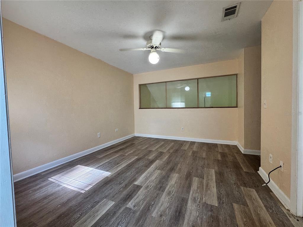 4224 Southwest 70th Terrace, Unit A Gainesville, FL 32608 - Photo 16 of 25 an empty room with wooden floor fan and windows