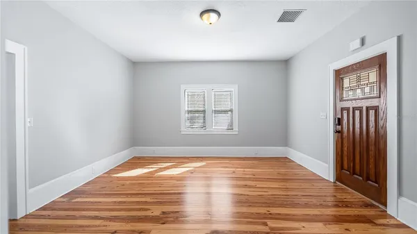 a view of empty room with wooden floor and fan