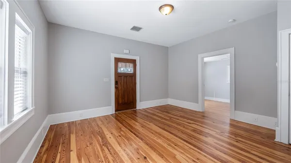 a view of an empty room with wooden floor and a window