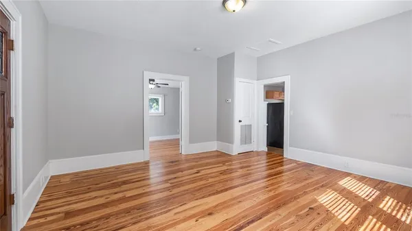 a view of an empty room with window and wooden floor