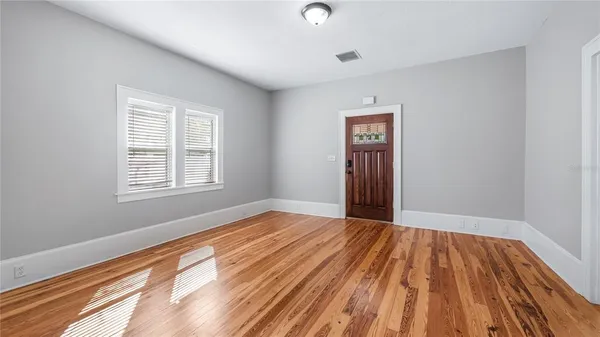a view of an empty room with wooden floor and a window