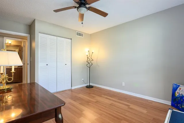 a view of a livingroom with a chandelier fan and wooden floor