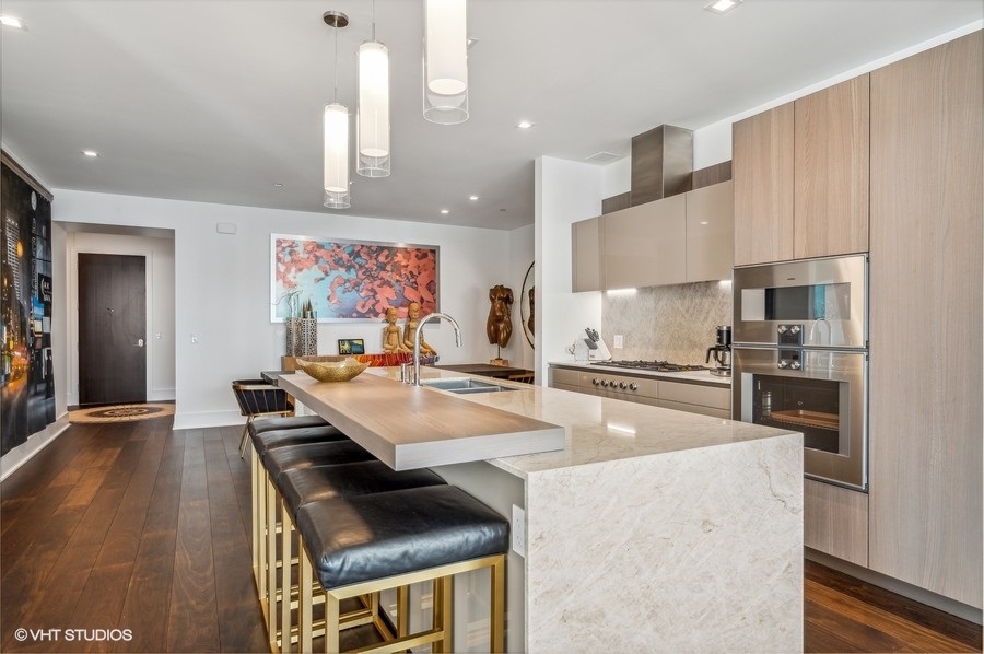 363 East Wacker Drive, Unit 2103 Chicago, IL 60601 - Photo 6 of 19 a large kitchen with kitchen island a stove a sink a refrigerator and white cabinets with wooden floor