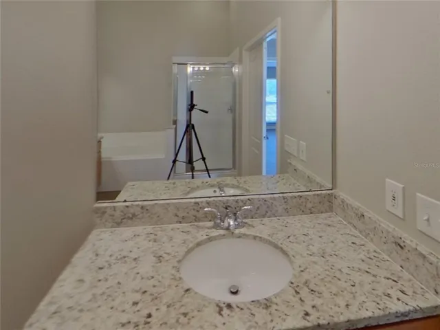 a bathroom with a granite countertop sink a mirror and a bathtub