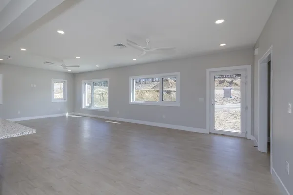 a view of an empty room with a window and wooden floor