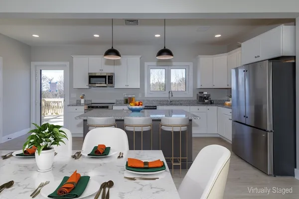 a kitchen with stainless steel appliances a refrigerator a sink a stove a dining table chairs and couches