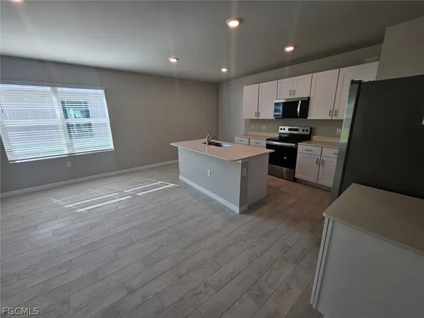 a kitchen with kitchen island granite countertop a sink cabinets and stainless steel appliances