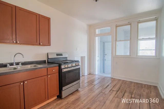 a kitchen with a sink wooden floor and black stainless steel appliances