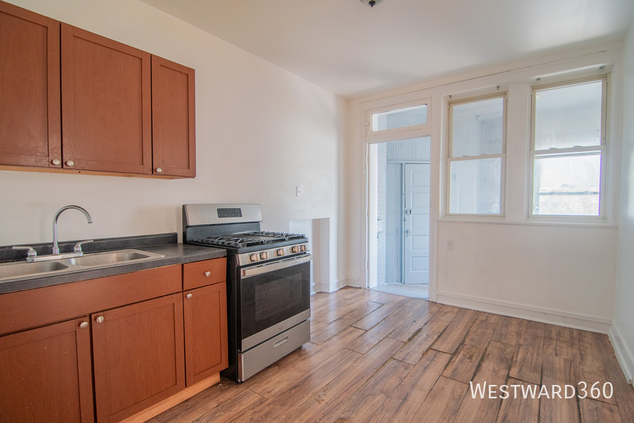 7833 South Kingston Avenue, Unit 2 Chicago, IL 60649 - Photo 12 of 15 a kitchen with a sink wooden floor and black stainless steel appliances