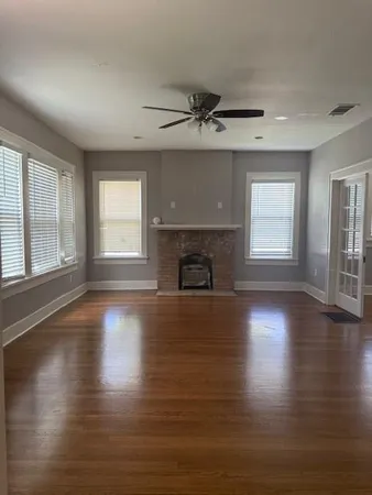 an empty room with wooden floor fireplace and windows