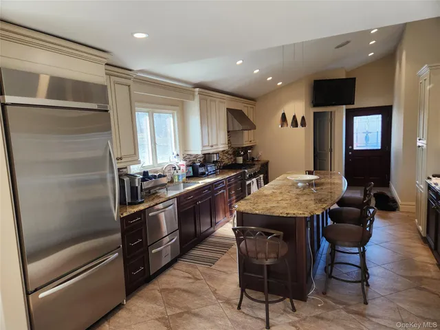a kitchen with stainless steel appliances kitchen island granite countertop a table chairs and a refrigerator