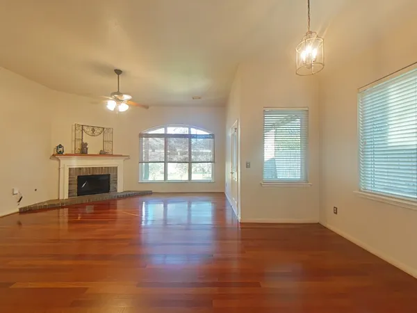 an empty room with wooden floor fireplace and windows
