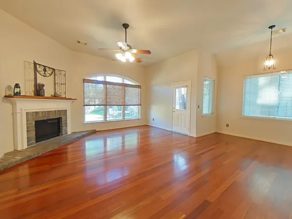 a view of an empty room with wooden floor fireplace and a window