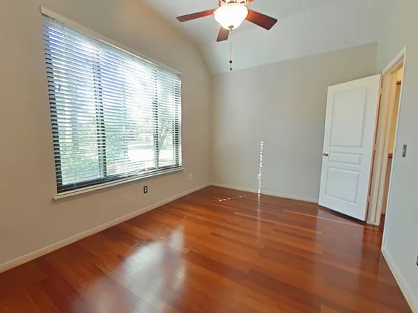 an empty room with wooden floor and windows