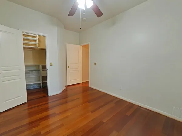 an empty room with wooden floor closet and windows