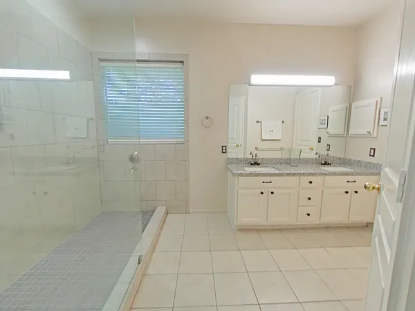 a spacious bathroom with a granite countertop sink a toilet a mirror and shower