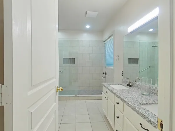 a bathroom with a granite countertop sink a mirror and a bathtub