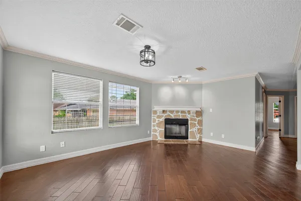 an empty room with wooden floor a fireplace and windows