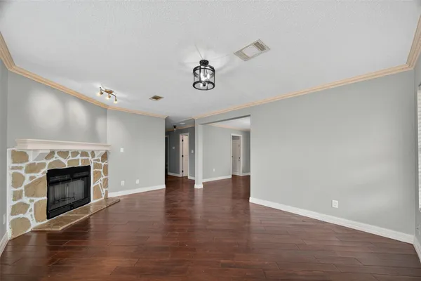 an empty room with wooden floor fireplace and cabinet