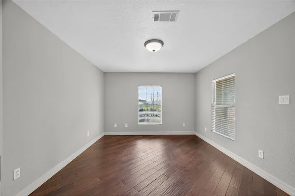 an empty room with wooden floor and windows