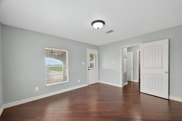 an empty room with wooden floor and windows