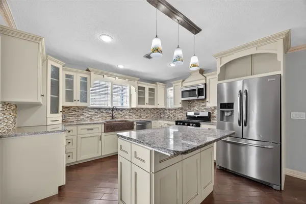 a kitchen with a sink stainless steel appliances and chandelier