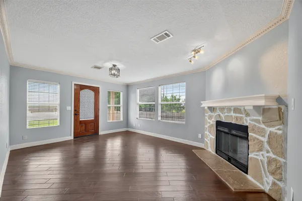 an empty room with wooden floor fireplace and windows
