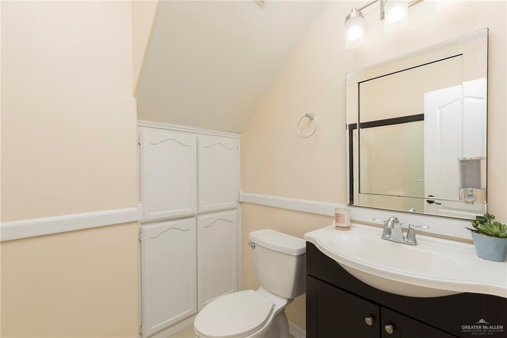 2001 Quail Lane Mission, TX 78572 - Photo 23 of 28 Bathroom featuring a dark wood vanity with an integrated white sink, a chrome faucet, and a large mirror with a beveled edge
