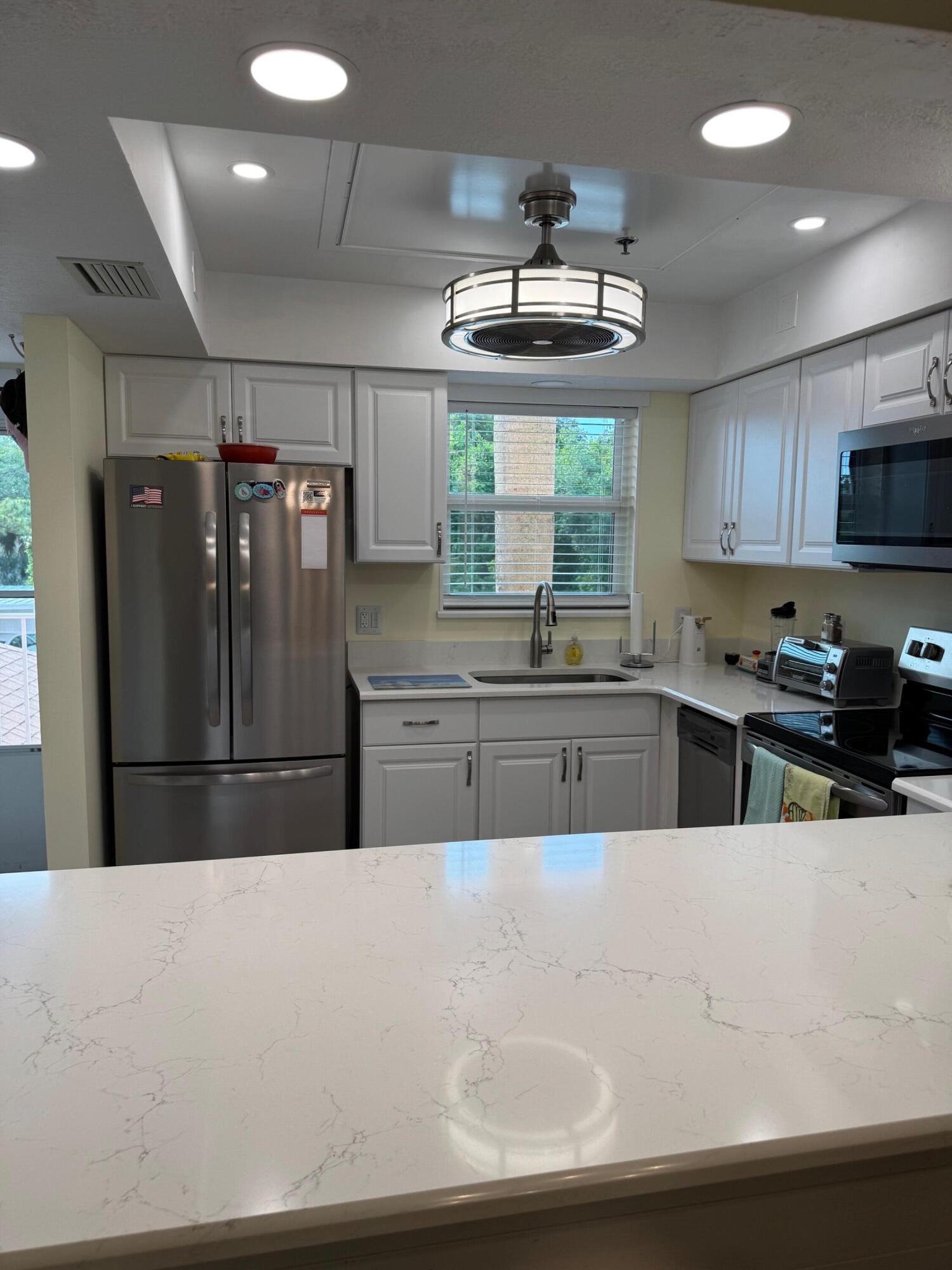 2950 Southeast Ocean Boulevard, Unit 110202 Stuart, FL 34996 - Photo 2 of 25 a kitchen with stainless steel appliances a refrigerator a sink a stove a center island and furniture