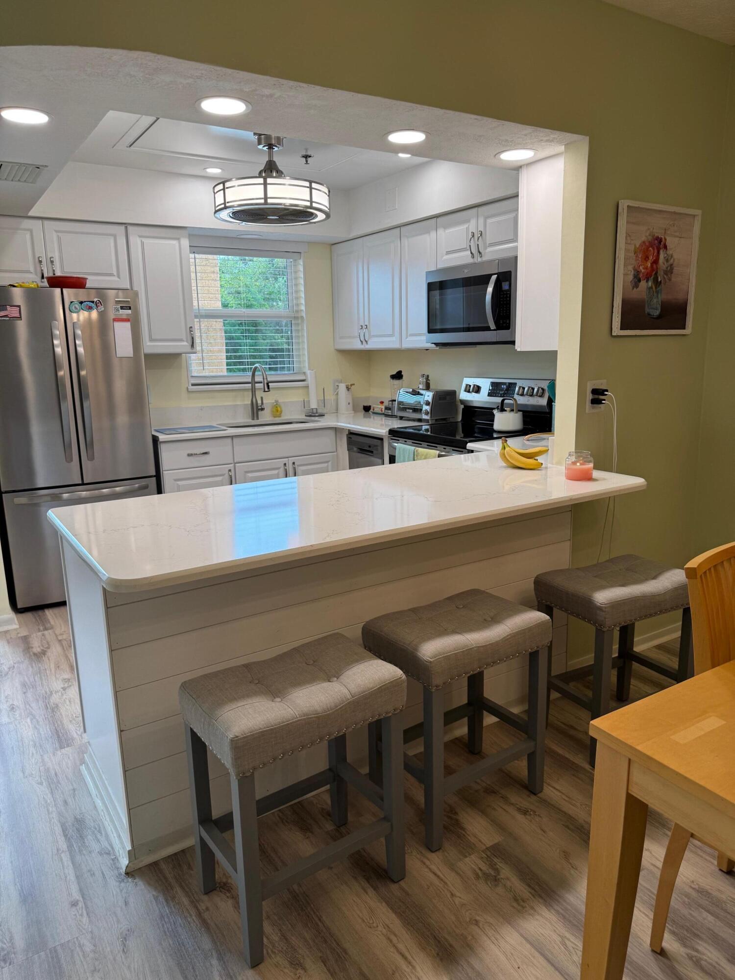 2950 Southeast Ocean Boulevard, Unit 110202 Stuart, FL 34996 - Photo 3 of 25 a kitchen with a table chairs refrigerator and microwave