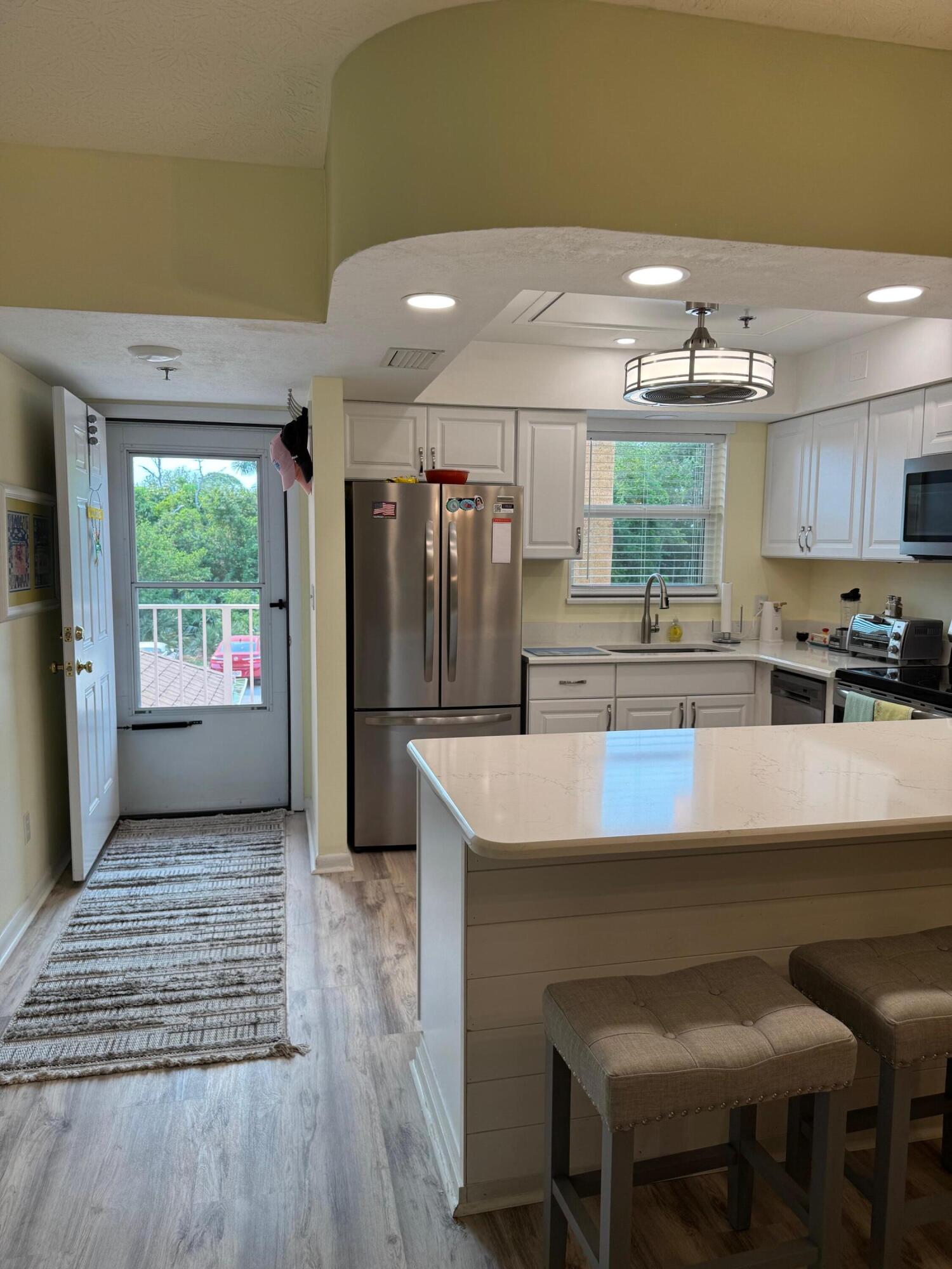 2950 Southeast Ocean Boulevard, Unit 110202 Stuart, FL 34996 - Photo 4 of 25 a kitchen with kitchen island a table and chairs in it